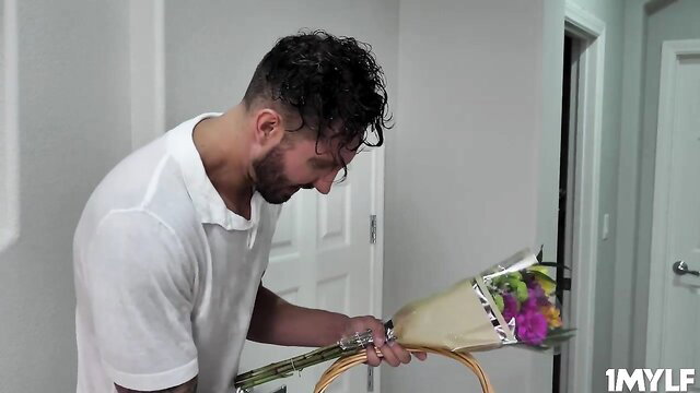 Quinton James with flowers at door in white polo shirt, MYLF scene